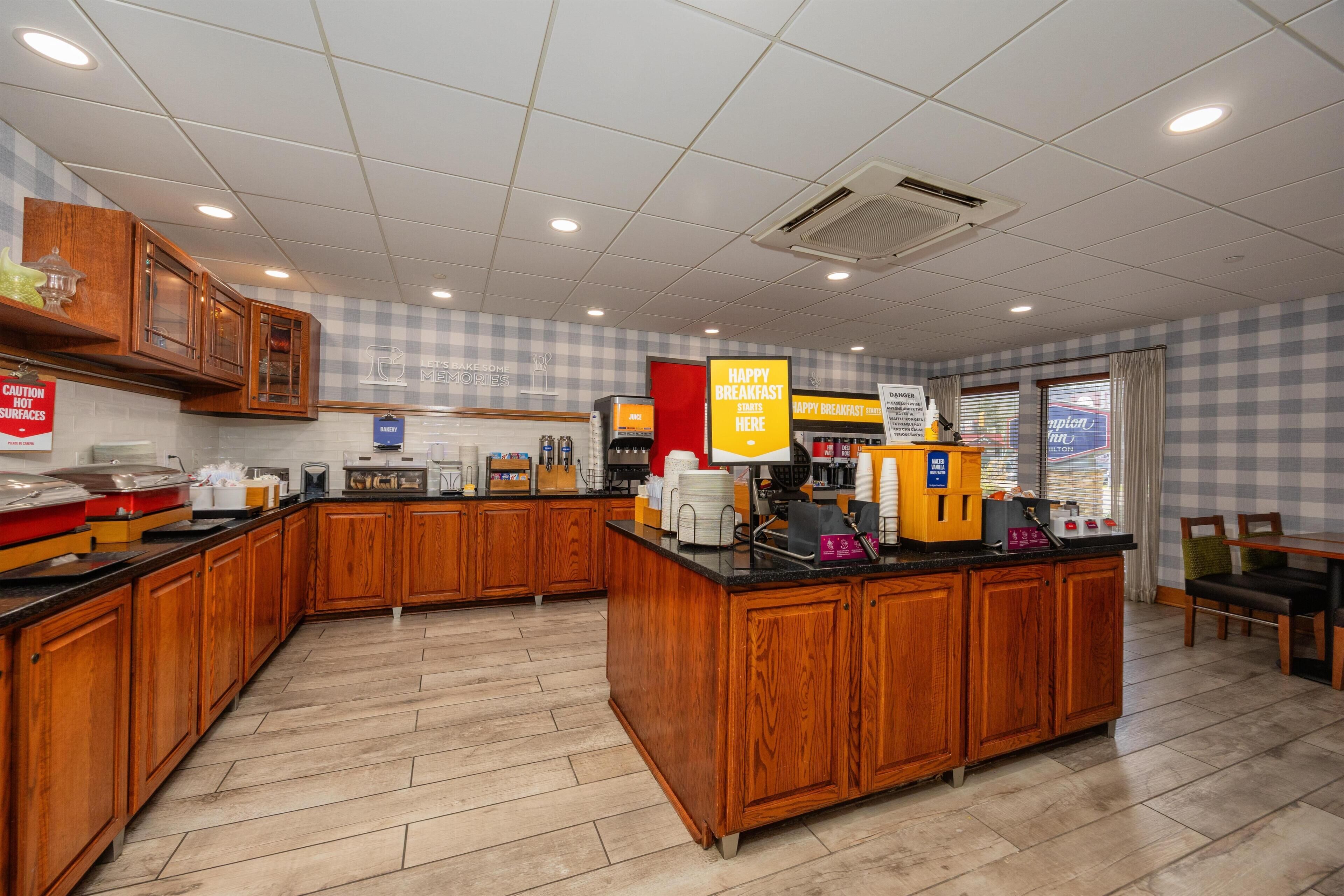 A breakfast area with wooden cabinets, a coffee station, and a checkered wall pattern.