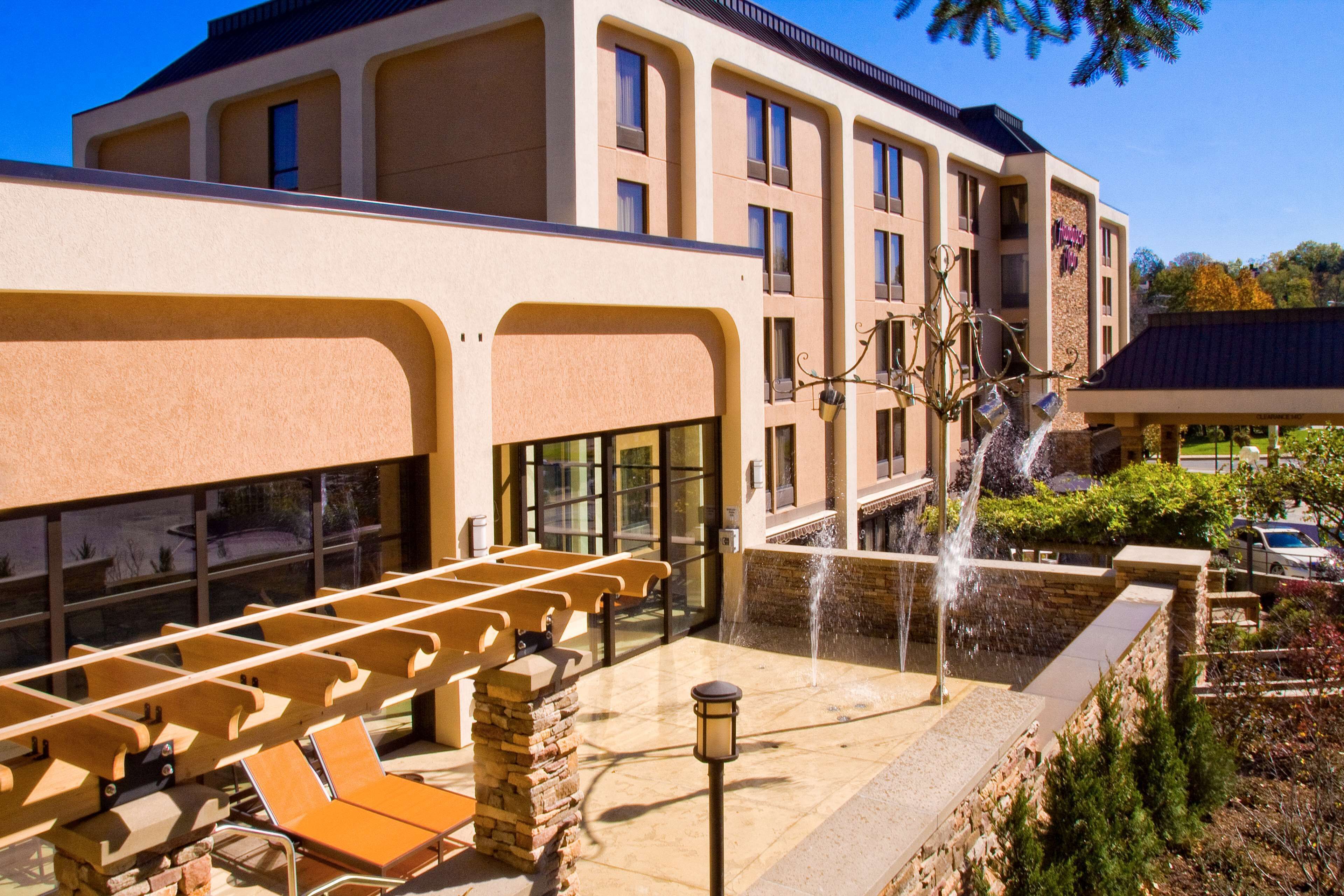 A hotel with a pool area, outdoor seating, and a water feature.