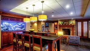 A bar area with wooden chairs, a large aquarium, and a fireplace. - Hampton Inn Wheeling (Wheeling)