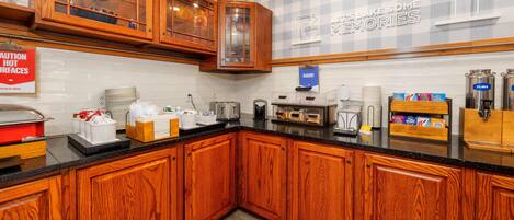 A kitchen with wooden cabinets, a glass-fronted cabinet, a sign reading 'BAKERY,' and a wall sign that says 'IT'S BAKESOME MEMORIES.'