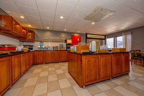 A spacious kitchen with wooden cabinets, a coffee station, and a breakfast bar.