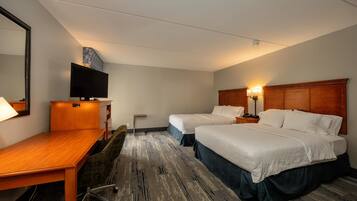 A hotel room with two beds, a desk, a chair, a television, and a mirror.