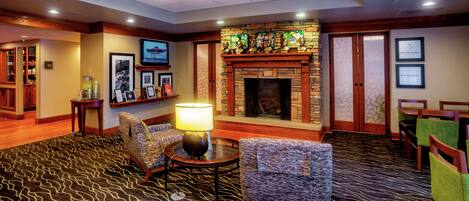 A lobby with a fireplace, seating area, and a television screen.