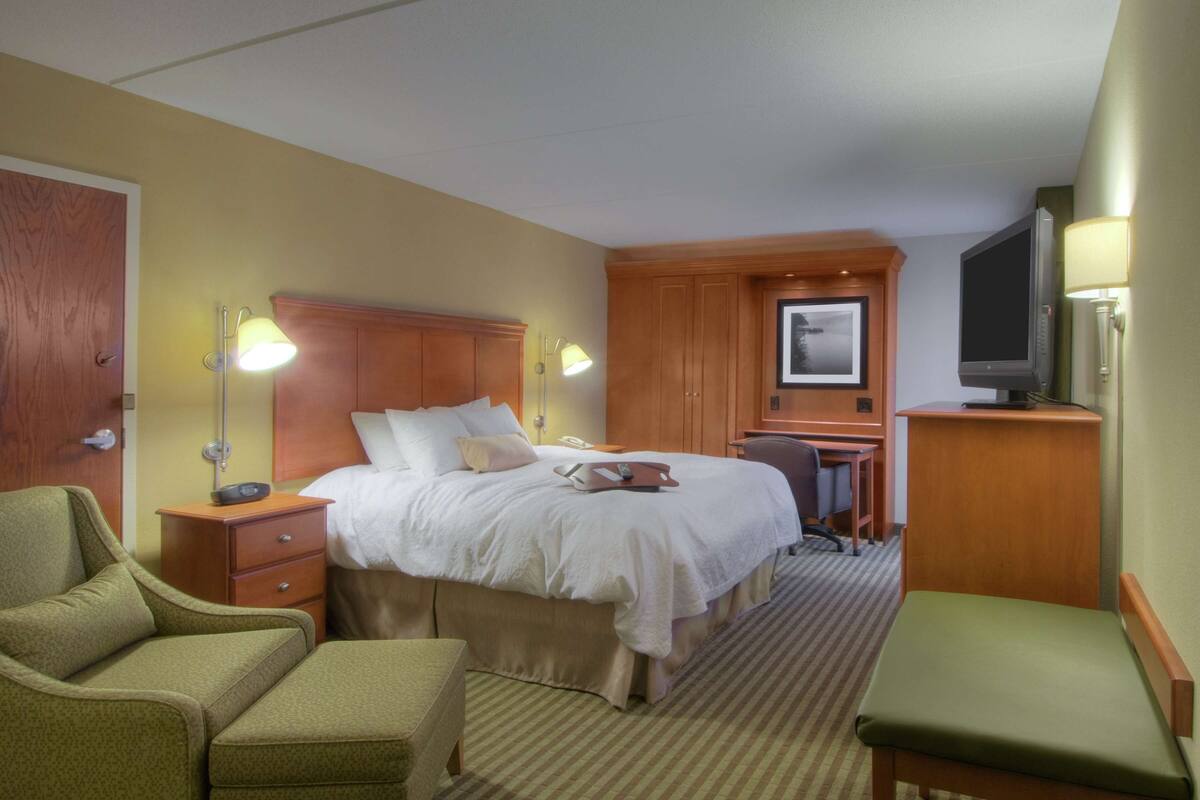 Una habitación de hotel con una cama, un escritorio, una silla, un televisor y una lámpara.