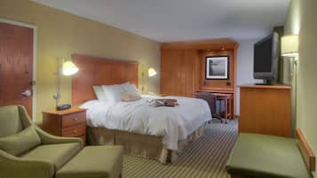 Una habitación de hotel con una cama, un escritorio, una silla, un televisor y una lámpara.
