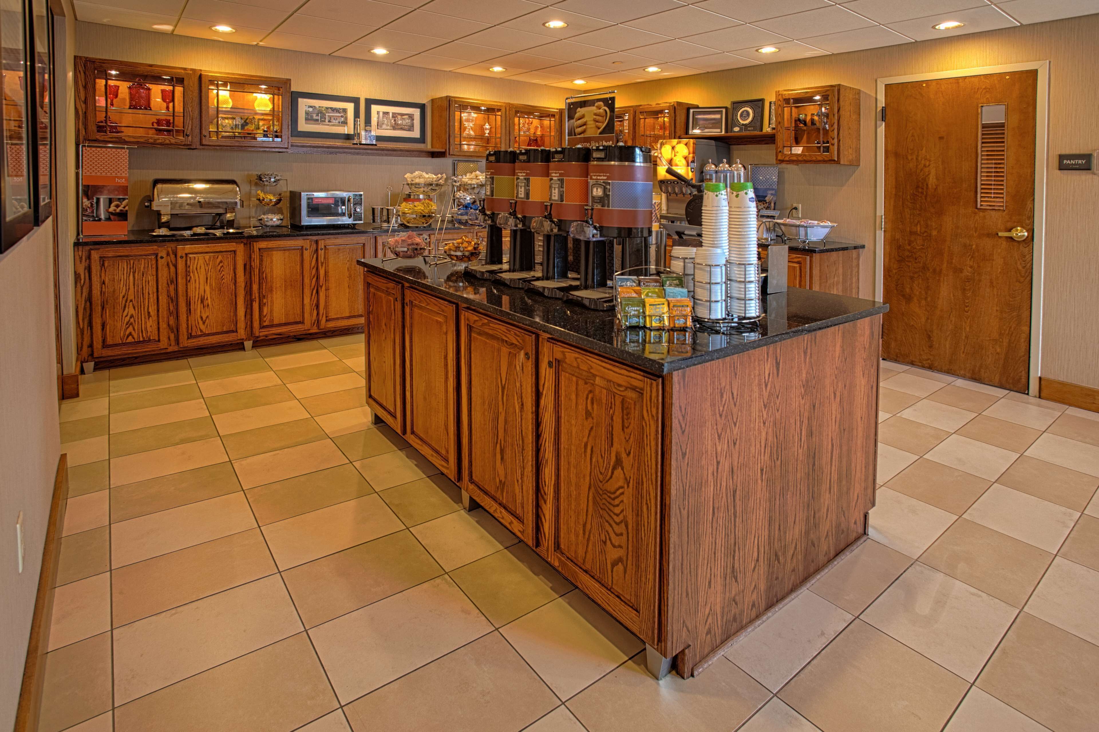 A kitchen with wooden cabinets, a central island, and various appliances including a coffee machine and microwave.