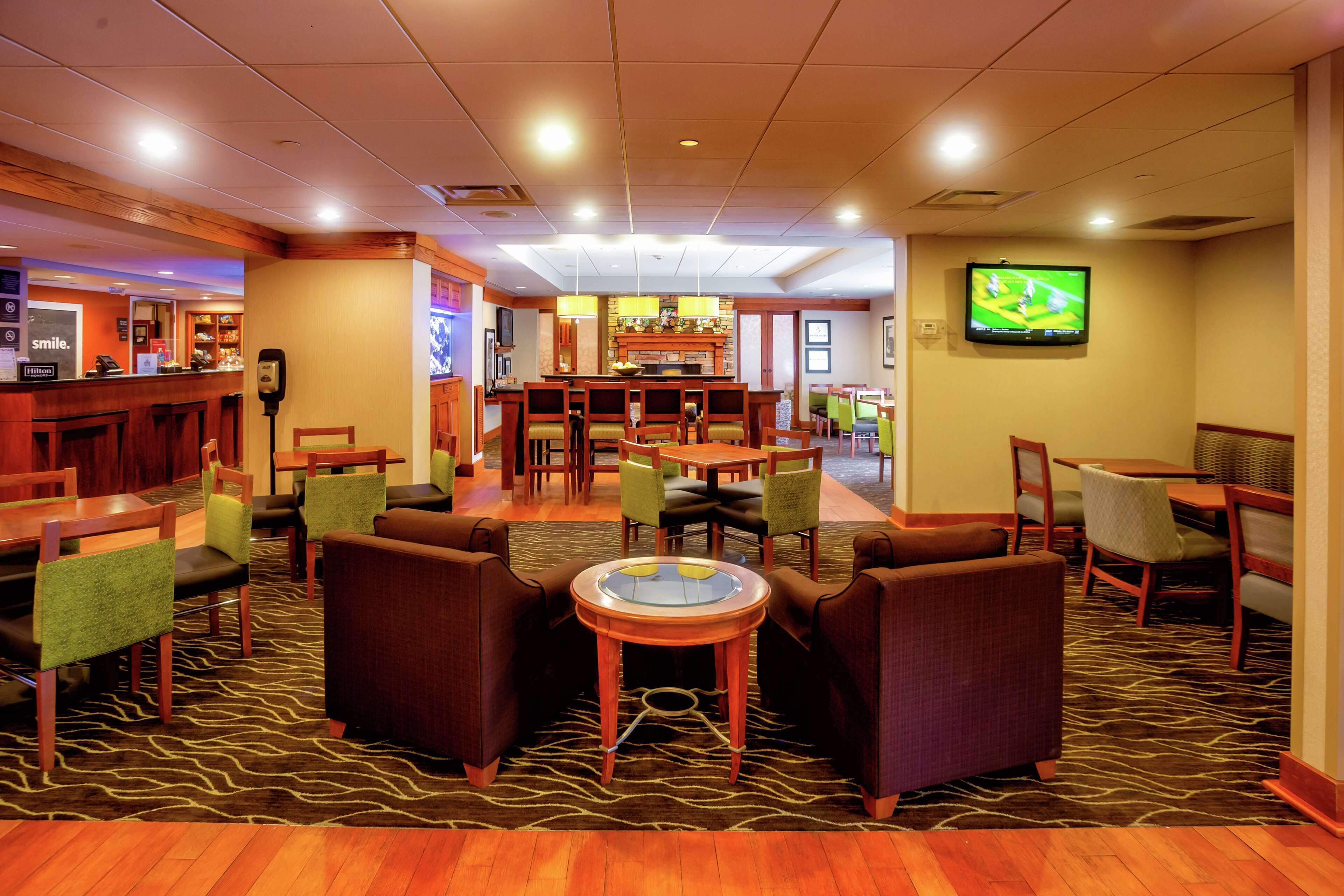 A hotel lobby with a bar area, seating arrangements, and a television screen.