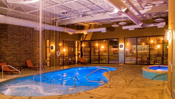 An indoor swimming pool with a hot tub, lounge chairs, and a brick wall. - Hampton Inn Wheeling (Wheeling)
