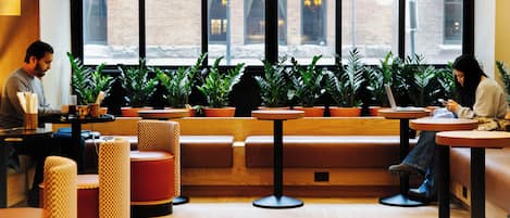 A cafe interior with seating arrangements, tables, and potted plants.