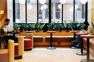 Een café interieur met zitplaatsen, tafels en potplanten.