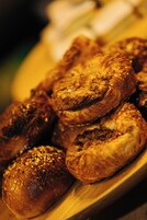 Een houten serveerplank met diverse gebakjes, waaronder croissants en broodjes.
