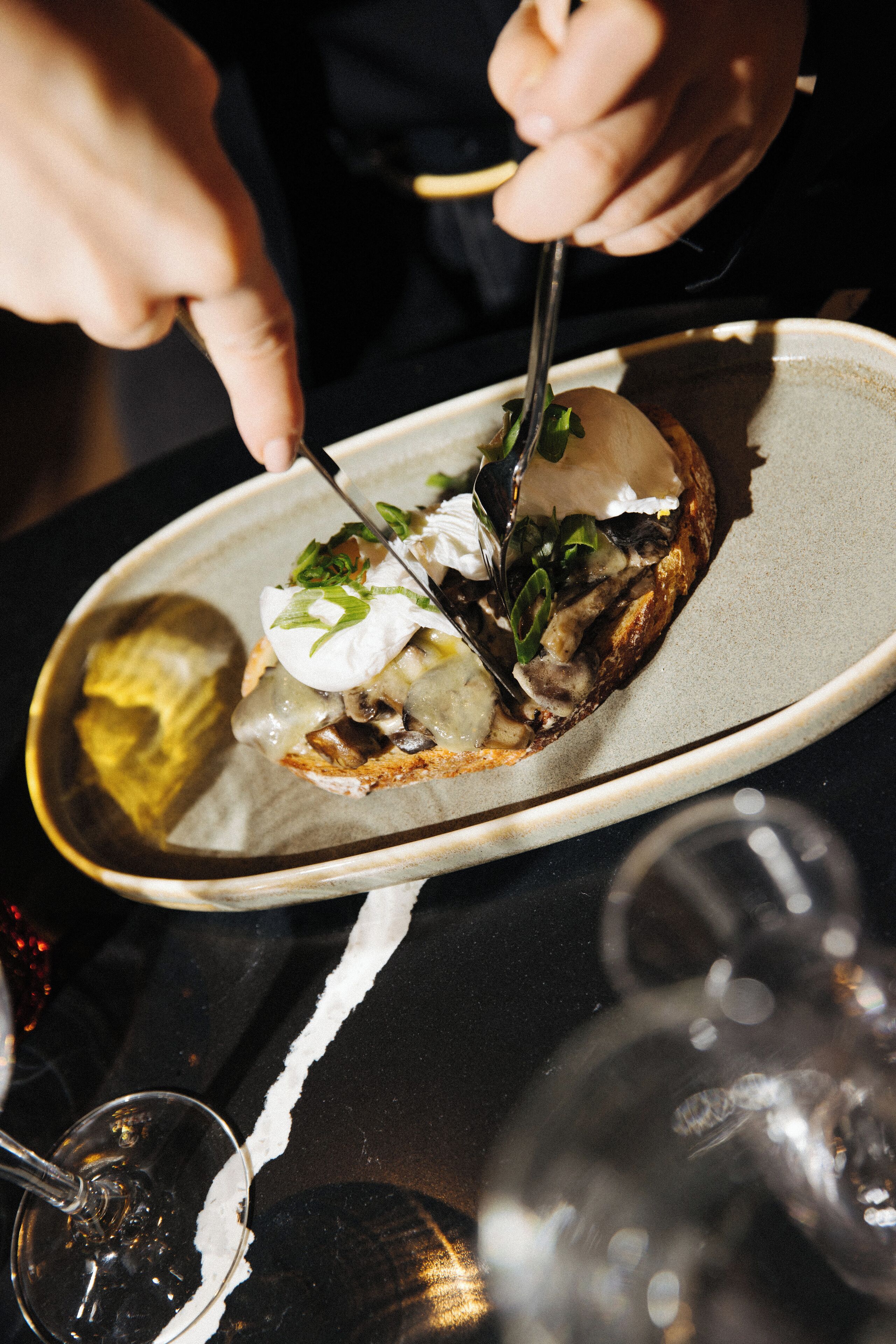 A person cutting a dish with a fork and knife on a plate.