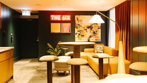 A modern hotel lobby with a neon sign, a round table, sofas, and a large abstract painting. - Union Hotel (Toronto)