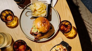Una comida con hamburguesa, papas fritas y bebidas sobre una mesa de madera.