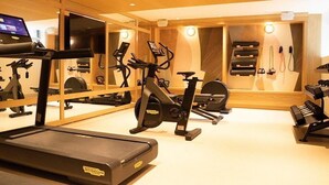 A gym with cardio machines, weights, and a TV screen. - Union Hotel (Toronto)
