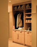 Een houten garderobe met meerdere planken, een kledingroede en een aanrecht met spullen.