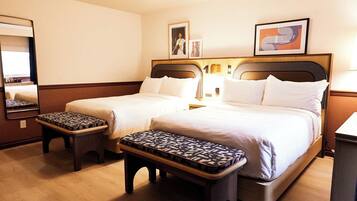 Een hotelkamer met twee bedden, een grote spiegel en een kleine tafel met een decoratief kussen.