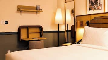 Een hotelkamer met een bed, nachtkastje, lamp, plank en een spiegel.