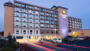 Un hotel Comfort Inn con fachada moderna, varios pisos y un estacionamiento con coches.