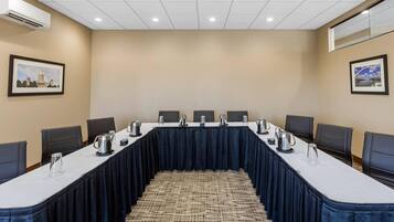 A conference room with a long table, chairs, and a carpeted floor.