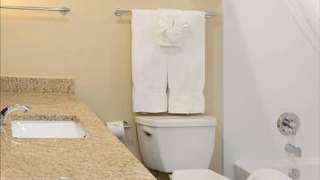 Un bagno con un piano lavabo in granito, un WC, una vasca da bagno e due quadri appesi al muro.