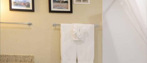 Un baño con encimera de granito, un inodoro, una bañera y dos cuadros en la pared.