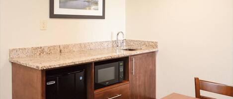 A compact kitchen with a microwave, dishwasher, and a framed picture on the wall.