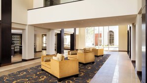 A spacious lobby with a high ceiling, a patterned carpet, and seating areas.