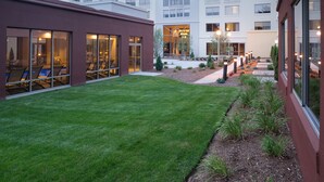 A courtyard with a well-maintained lawn, outdoor seating area, and a building with large windows and balconies.