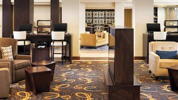 A hotel lobby with a reception desk, two computer stations, a sofa, and a patterned carpet.