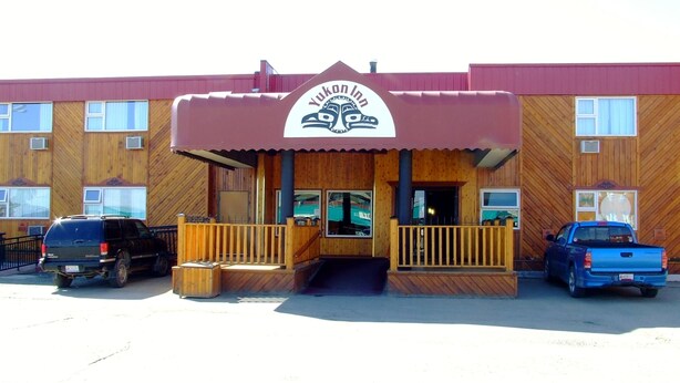 A wooden building with a sign reading "Yukon Inn" and a covered entrance. - Yukon Inn (Whitehorse)