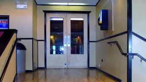 A staircase leading to a double door with a glass panel, a trash bin, and a wall-mounted device. - Yukon Inn (Whitehorse)