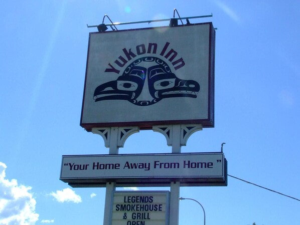 A sign for Yukon Inn with a totemic design and a slogan 'Your Home Away From Home'.