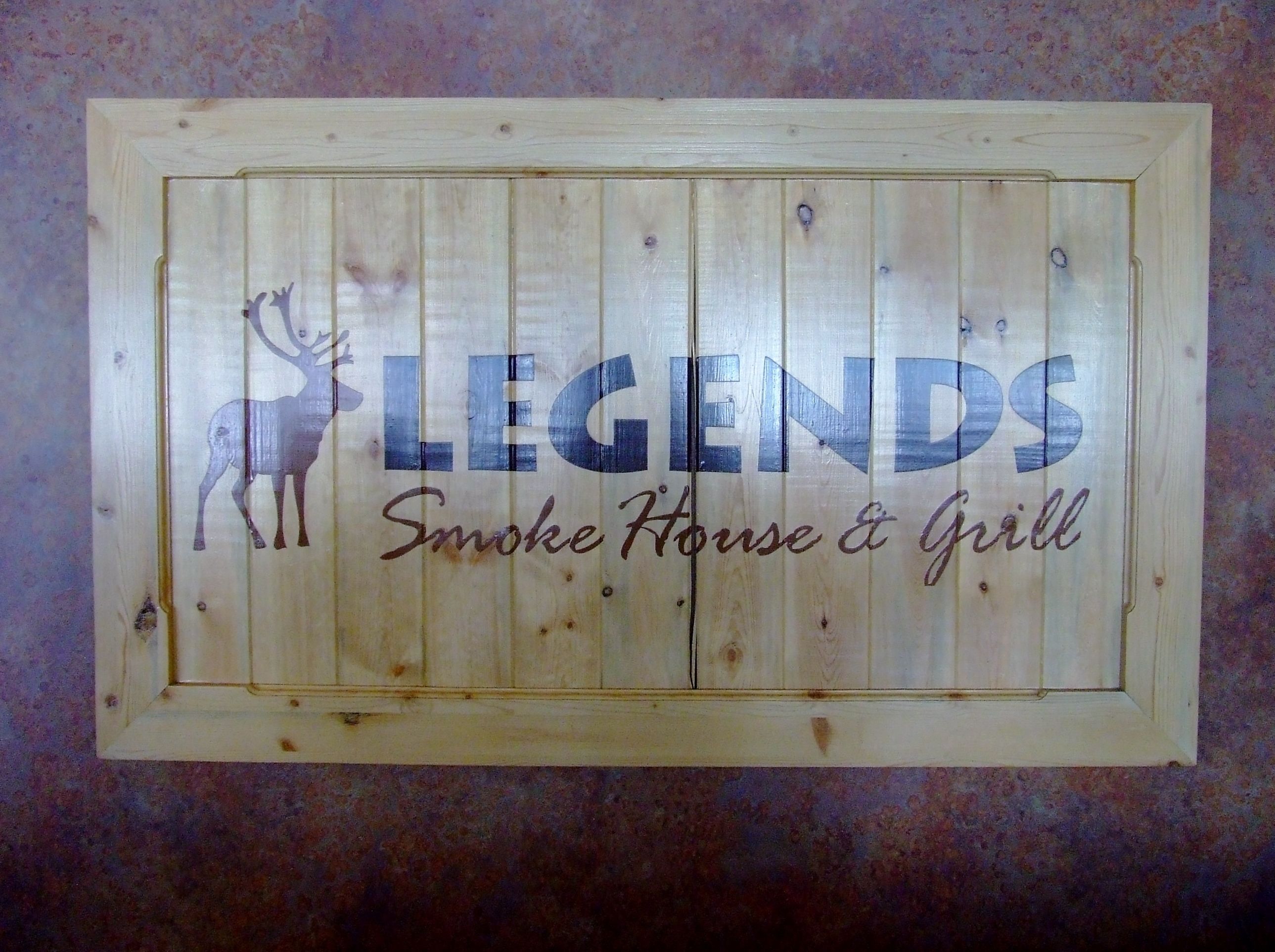 A wooden sign with the text "LEGENDS Smoke House & Grill" and a deer silhouette.
