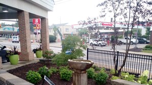 Un bac à fleurs en pierre agrémenté d’une fontaine, entouré d’un mur de briques et de plantes en pot.
