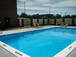Una piscina al aire libre, sillones reclinables de piscina