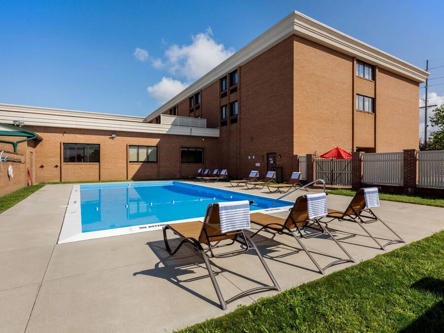 A swimming pool with lounge chairs, a brick building, and a clear sky.