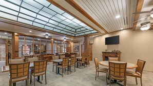 Un grand espace intérieur doté d’un haut plafond, d’une verrière et de nombreuses tables et chaises.