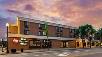 A hotel with a 'Best Western PLUS' sign, brick facade, and multiple storefronts.