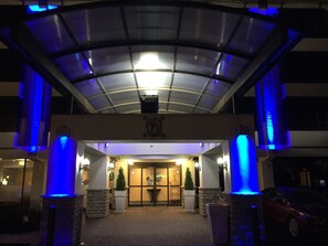 A hotel entrance with a covered entrance, stone pillars, and a glass door leading to the lobby. - Holiday Inn Express Detroit-Birmingham by IHG (Birmingham)