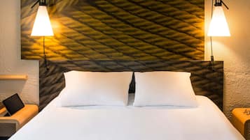 A neatly made bed with white linens, two bedside lamps, and a textured wall behind.