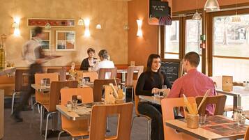 A restaurant interior with tables, chairs, and hanging pendant lights.