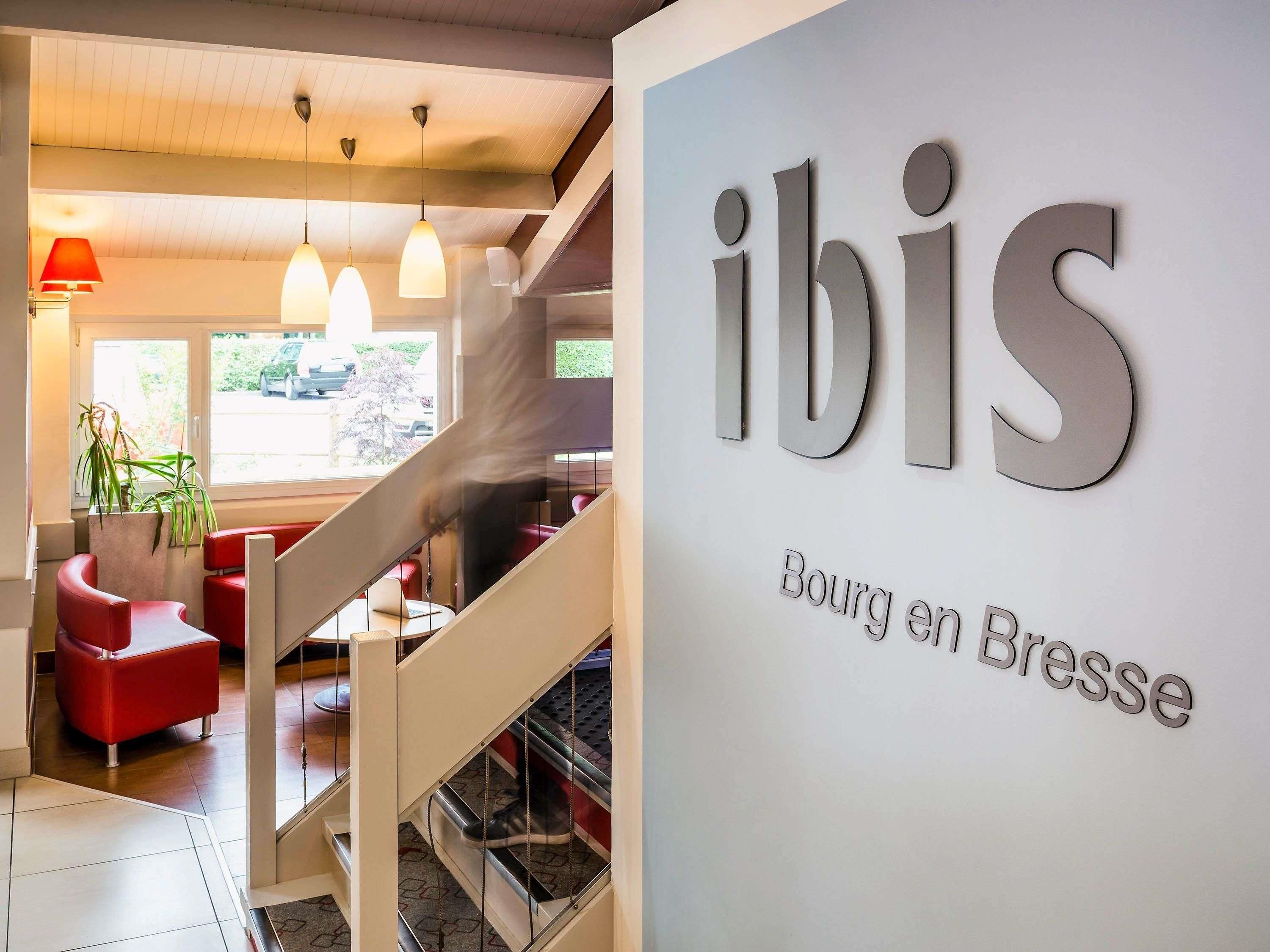 Un interior moderno con una escalera, asientos rojos y un letrero que dice 'ibis Bourg en Bresse'.