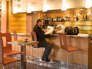 Un espace bar avec des tabourets, un comptoir et une variété de bouteilles.