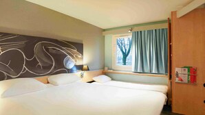 A hotel room with a large bed, a window with curtains, a wall with a chalkboard, and a shelf with items. - ibis Bourg En Bresse (Bourg-en-Bresse)