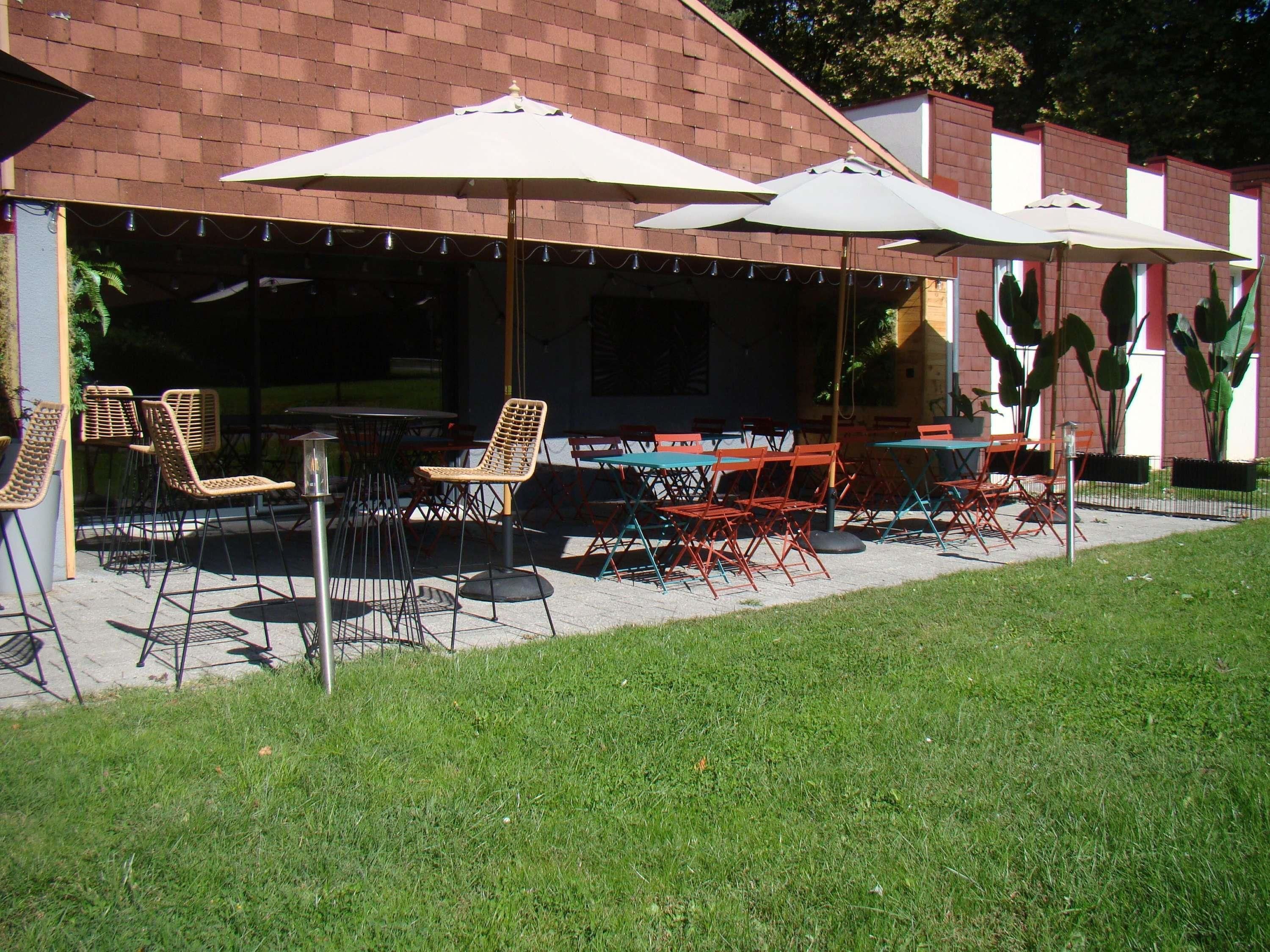 Une terrasse extérieure avec des tables et des chaises, des parasols et des plantes en pot.