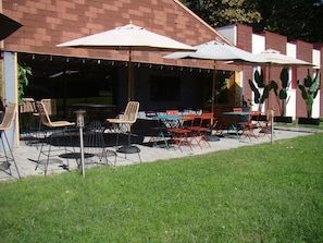 Un patio al aire libre con mesas, sillas, sombrillas y plantas en macetas.