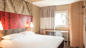Una habitación de hotel con cama, escritorio y armario.