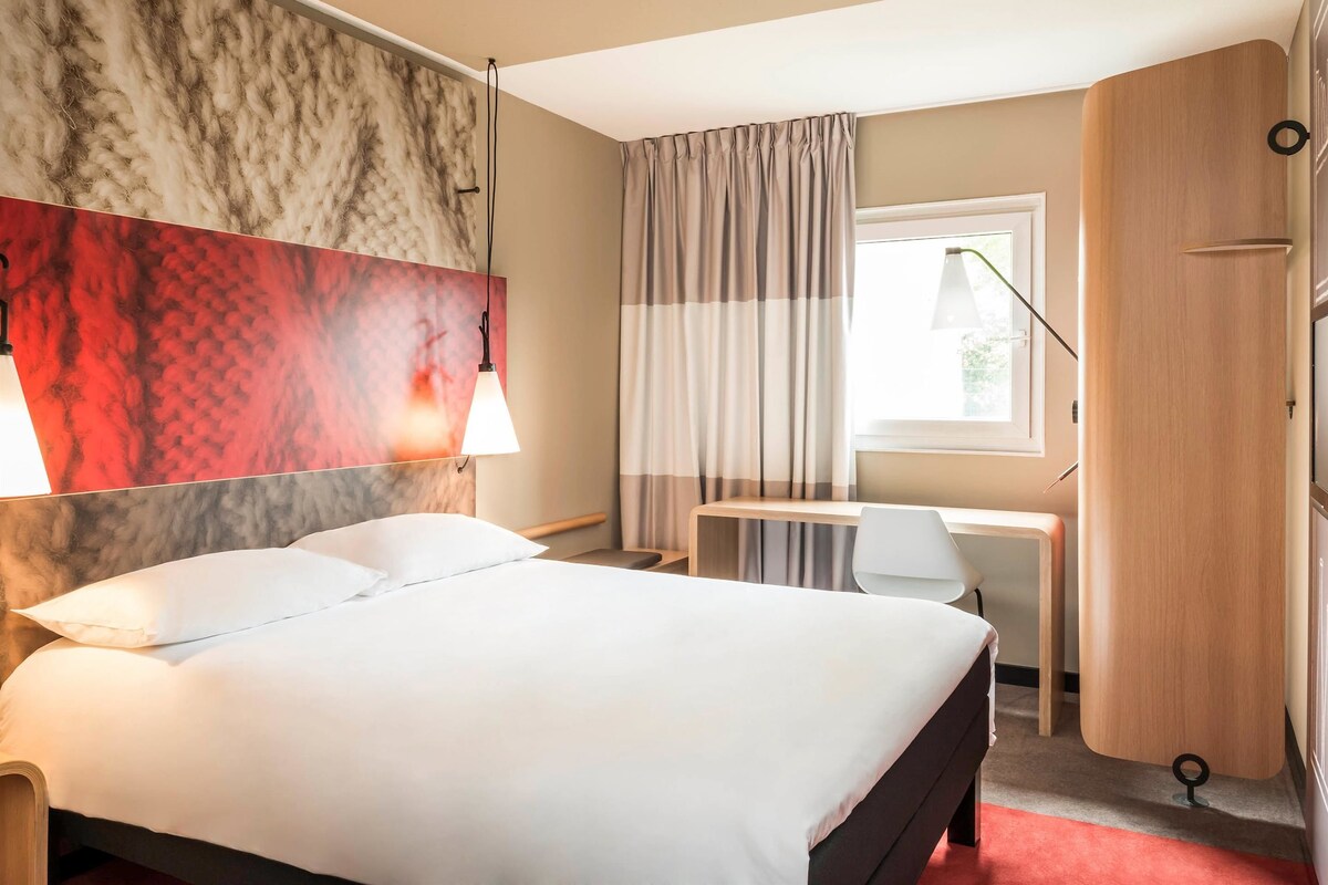 Una habitación de hotel con cama, escritorio y armario.