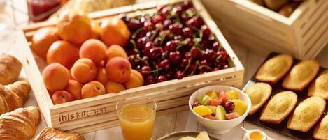 A breakfast setting with fruits, pastries, and a glass of orange juice.